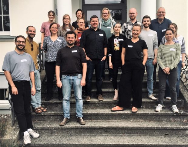 17 Workshopteilnehmende stehen auf der Treppe zum Eingang in das Verwaltungsgebäude des Naturparks Barnim. Alle Teilnehmenden lächeln und wirken gut gelaunt. (Foto: Eva Roeder)