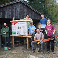 Hier sehen Sie ein Bild von britischen Studenten vor ihrer selbst gebauten Infotafel nahe der Friedrichshütte bei Söllichau