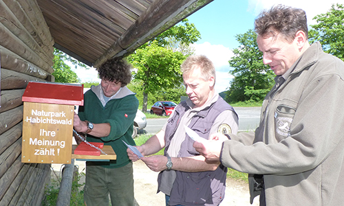 Jan Lippke (Mitte) zeigt sich begeistert vom mobilen Kummerkasten, der an wechselnden Punkten im Naturpark Habichtswald eingesetzt werden kann, um die Meinung der Gäste zu erfragen. Mit im Bild: Uwe Hartmann (links) und Jürgen Depenbrock, Geschäftsführer Zweckverband Naturpark Habichtswald (rechts). NP Scouting Auf dem Weg zum Qualitäts Naturpark Naturpark Habichtswald stellt sich dem nationalen Vergleich