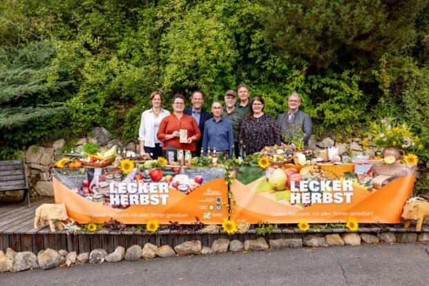 Eröffnung der "Lecker -Herbst-Saison 2026 mit 8 Vertreter*innen der Naturparke und der Volksbank Kassel Göttingen hinter einer Plane mit der Aufschrift Lecker Herbst. © Volksbank Kassel Göttingen