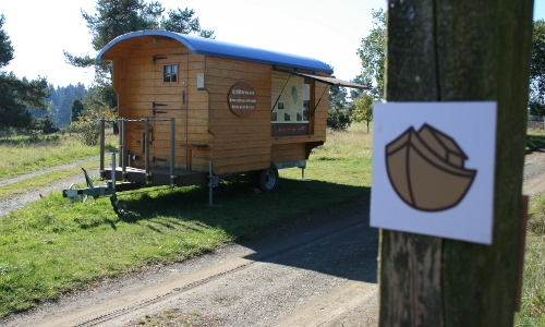 Markierungspfosten mit Logo am Arche-Erlebnispfad, daneben der Schäferwagen des Naturparks © Reiner Ohlsen