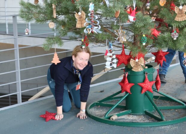 Dr. Aija Torkler, Leiterin Naturpark Barnim, kniet beim Schmücken links unter dem Baum. © Achmed Polzin